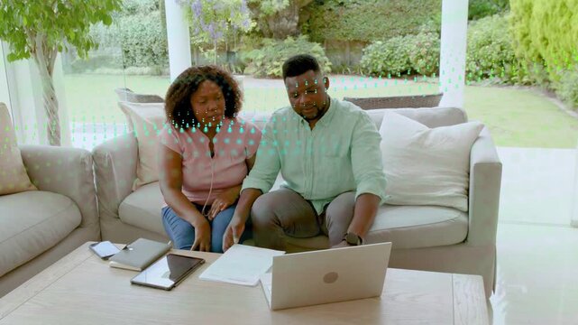 Holding hands, talking, couple shuffling docs, angling laptop, grabbing pen, reviewing finance