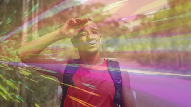 Male hiker shielding eyes from glare, scanning road, light streaks sweeping over backpack, travel