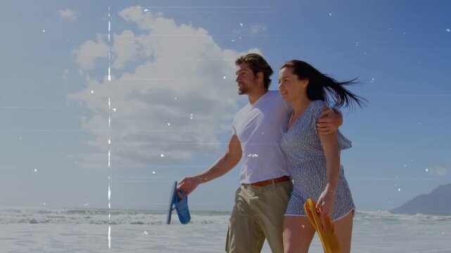 Travel couple walking beach, man linking arm and pointing horizon sharing view, holding flip-flops