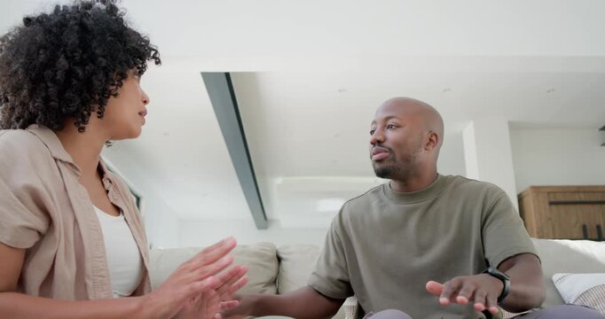 African American couple arguing on sofa, man showing phone then standing, woman holding head