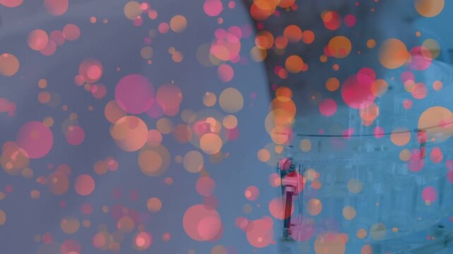 Gloved hand entering right, adjusting lid knob, tilting can into inlet loading vessel, bokeh rising