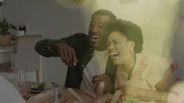 Couple reacting to guest motion at table laughing and leaning in bokeh circling them accenting food