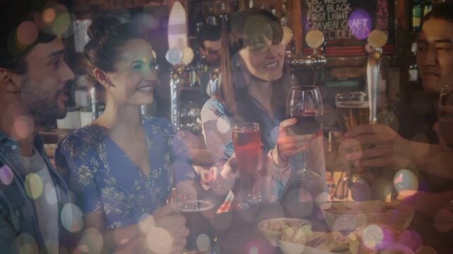 Friends at bar raising glasses after woman lifting wine glass, animated bokeh highlighting toast