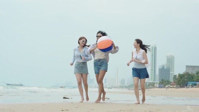 Joyful slow-motion video of three young diverse female friends running and simultaneously jumping together on a tropical sandy beach during a sunny summer vacation.