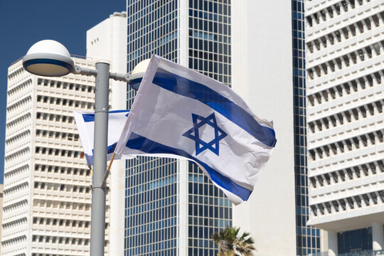 Israeli flag waving in the wind in front of the iconic Shalom Meir Tower in Tel Aviv, Israel. symbol of national pride against the backdrop of a major city landmark during a bright sunny day now