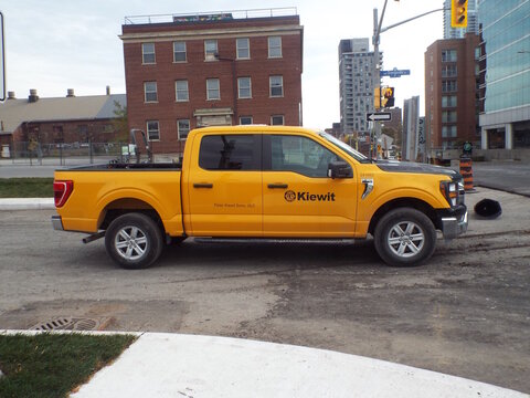 Ottawa, Ontario, Canada &ndash; August 02, 2025: A bright yellow "Kiewit construction pickup truck" is parked on a city street near an intersection and urban buildings on Orangeville St.
