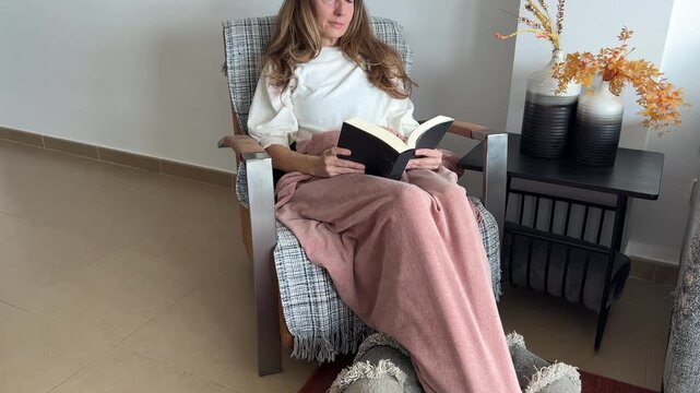 Mujer relajada en el sill&oacute;n leyendo un libro