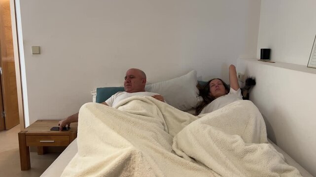 Pareja despert&aacute;ndose y apagando la alarma del tel&eacute;fono