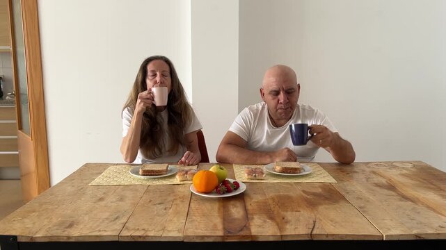 Pareja desayunando y conversando en pijama