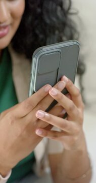 Vertical video: Woman holding phone with card, shifting grip, tapping screen, reading texts on sofa