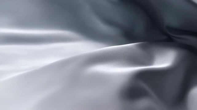 Slow motion tracking close up of fabric rippling and folding on studio surface with silver satin texture and minimal backdrop