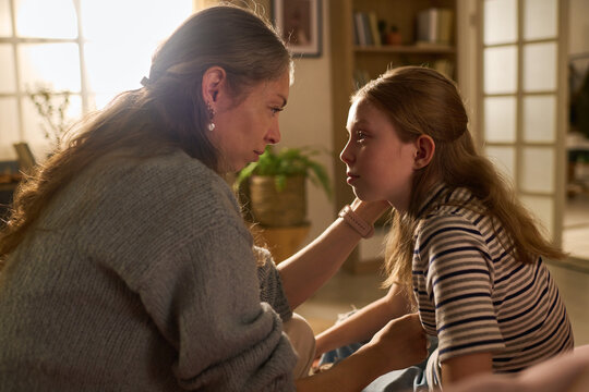 Caucasian mother comforting girl child while talking face to face at home, showing emotional support and trust. Ideal for parenting guidance, family counseling, mental health campaigns
