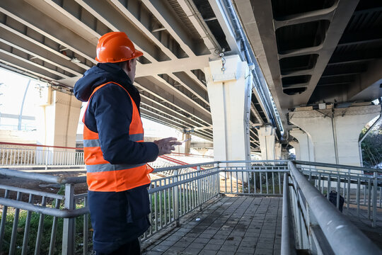 Engineer gesturing toward bridge supports during inspection