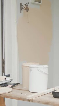Vertical video: Pouring paint into tray, man in white tee touching up entry wall by bell vent