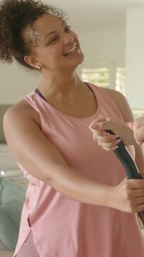 Vertical video: Helping partner start workout, woman in pink tank guiding elliptical at home, watch