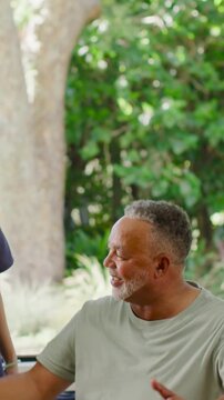 Vertical video: After aide placing hand, man in green T doing breaths to steady on ball on patio