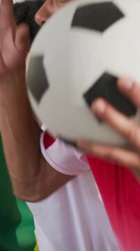 Vertical video: Cheering fans in red white tees reacting to goal at home holding soccer ball, watch