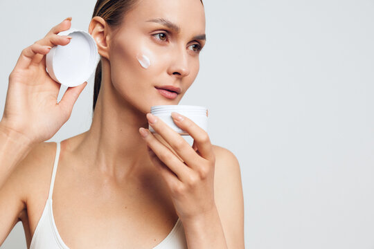 woman skincare face cream beauty hygiene moisturizing routine closeup a woman applies skincare cream with cotton pads clean light on background in morning for fresh skin care