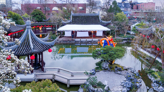 View of Lan Su Chinese Garden featuring traditional pavilions, red lanterns, and a dragon sculpture by the pond in Portland, Oregon, United States.