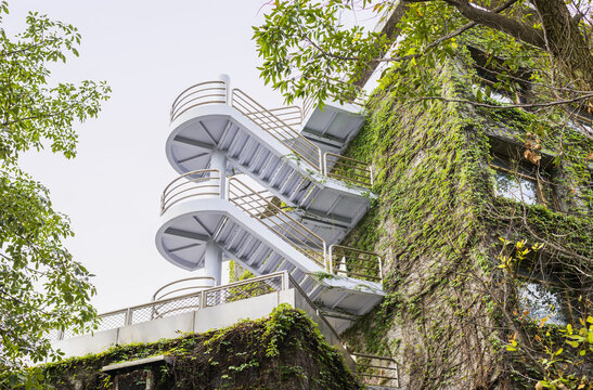 View of a modern white external staircase attached to a building facade covered in lush green ivy Taiwan.