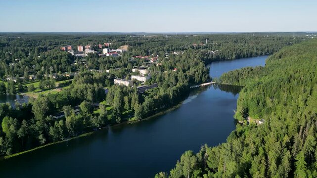 Aerial drone view of a lakeside beach in Kangasala, Finland, captured on a bright sunny summer day. Clear water, sandy shoreline, and surrounding green forest create a peaceful Nordic summer landscape