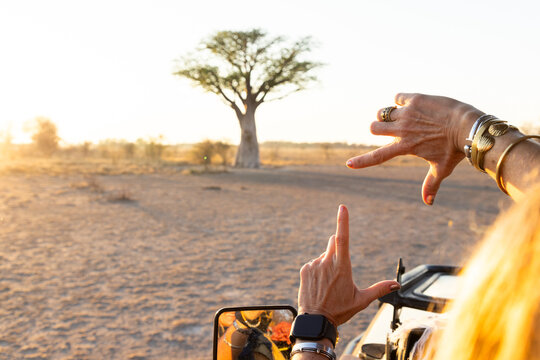 woman framing a baobab tree with her hands, Makgadikgadi National Park, Botswana, Africa