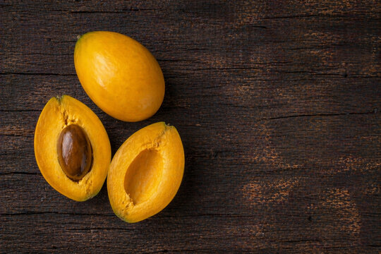 Canistel eggfruit sliced and whole tropical fruit on wood copy space