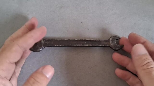 Vintage metal wrench being held by hands during a hands on mechanical repair project motion clip