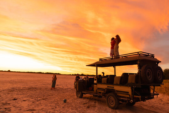 Family on vacation experiencing sunset over the Nxai Pan, Kalahari Desert, Botswana, Africa