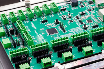 Fototapeta premium Electronic printed circuit board with multiple capacitors, microprocessor chips, ports and other electronic components on a production bench for manufacturing and diagnostics
