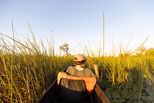child in traditional makoro boat, navigating the Okavango Delta, Botswana, Africa