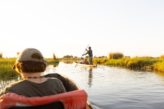 child in traditional makoro boat, navigating the Okavango Delta, Botswana, Africa