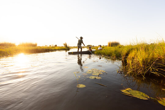 child in traditional makoro boat, navigating the Okavango Delta, Botswana, Africa