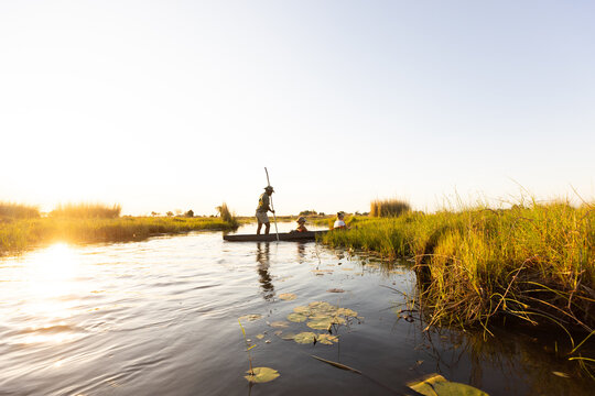 child in traditional makoro boat, navigating the Okavango Delta, Botswana, Africa
