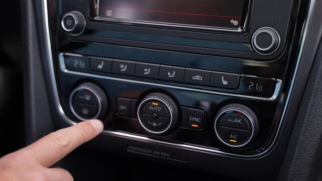 Hand pressing car climate control button slow motion
