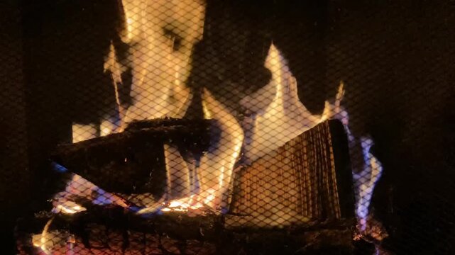 4k still footage of burning wood inside a chimney with grid on foreground and lots of flames, sparks and smoke