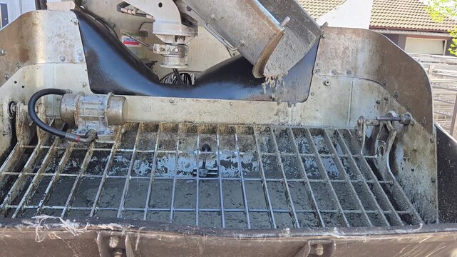 Wet concrete mixture falling into the hopper of a concrete pump machine.