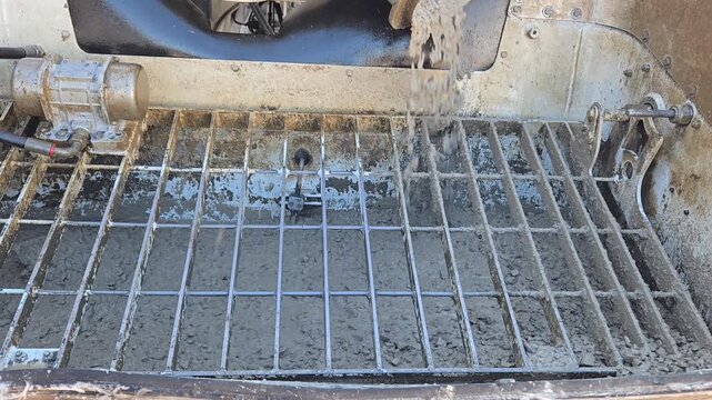 Wet concrete mixture falling into the hopper of a concrete pump machine.