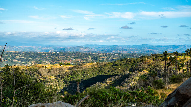 View of the rolling hills and lush green landscape of Splitrock Baby Oaks under a bright blue sky in Fallbrook, California, United States.