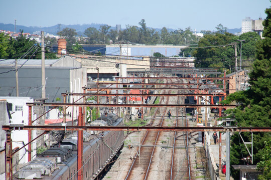 Railway line with parallel tracks and a train stopped on a side track, possibly used for waiting, maintenance, or operational control, surrounded by urban infrastructure and vegetation.