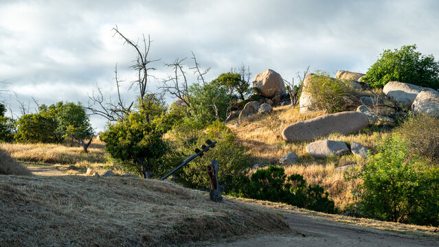 View of Splitrock Baby Oaks featuring large granite boulders and scattered oak trees under a cloudy sky in Fallbrook, California, United States.