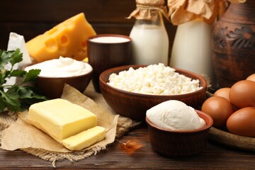 Fototapeta premium Many fresh dairy products, parsley and eggs on wooden table against dark background, closeup