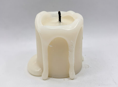 A single white candle with a black candlestick protruding from the wax