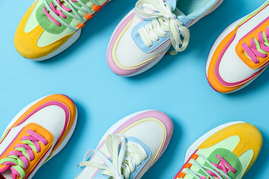 Stylish bright sneakers on light blue background, flat lay