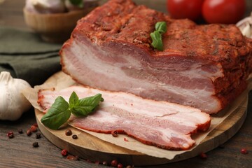 Fototapeta premium Pieces of smoked bacon, tomatoes and spices on wooden table, closeup