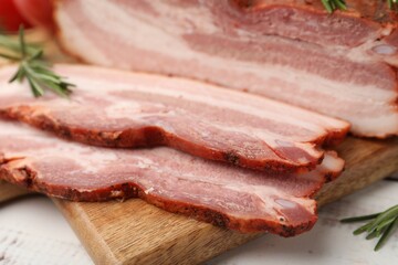 Fototapeta premium Pieces of smoked bacon on light grey wooden table, closeup