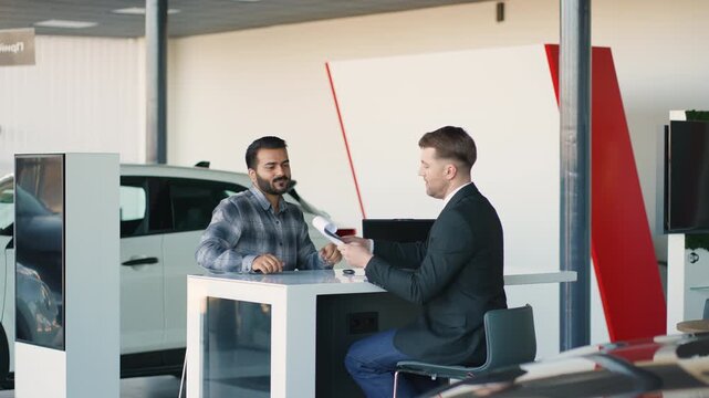Indian customer signing a contract with car dealer in showroom