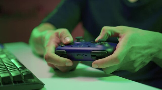 Gamer gripping red controller in dark hoodie, lowlit room with neon green PC and blurred monitor, closeup on hands and controller, tense focused mood, latenight stream atmosphere