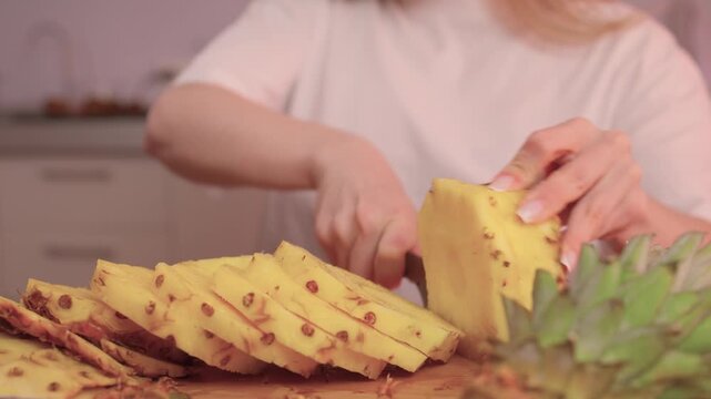 Closeup of pineapple slicing process. Hands expertly cutting pineapple into rings. Closeup footage showcasing detailed process of preparing fresh pineapple for cooking