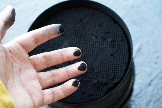 person with fingers stained with a carbon-saturated DPF